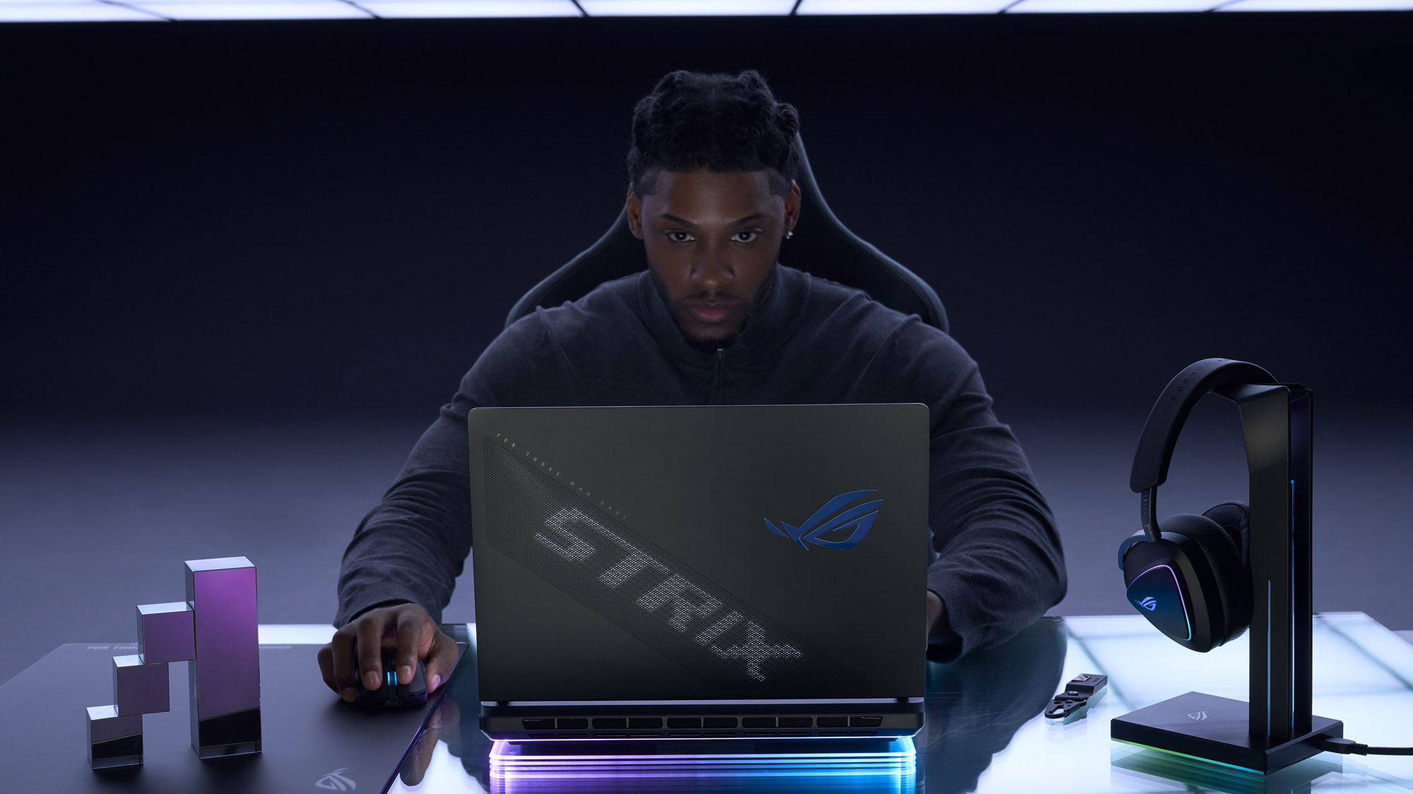 A man looking at an ROG Strix SCAR laptop with the back of the lid visible.